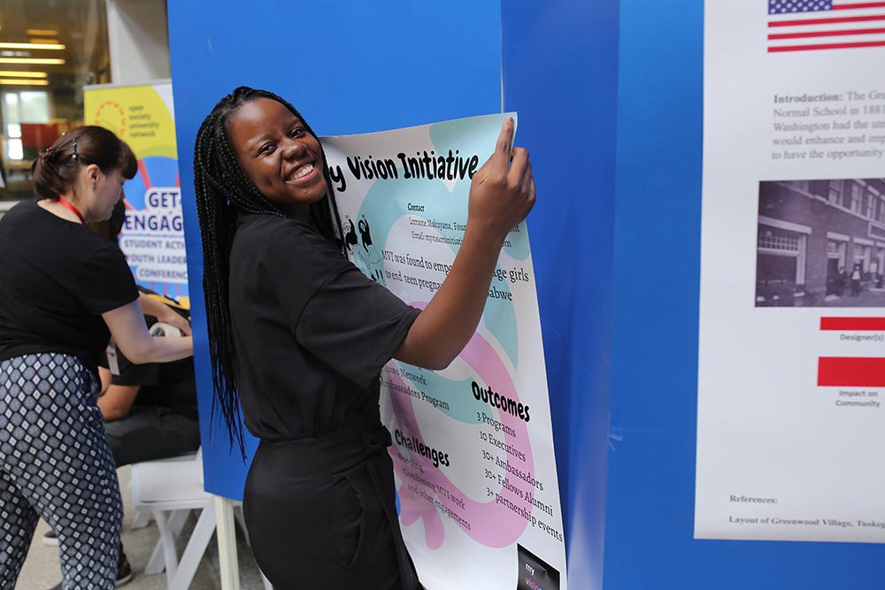 Young woman putting up her research poster