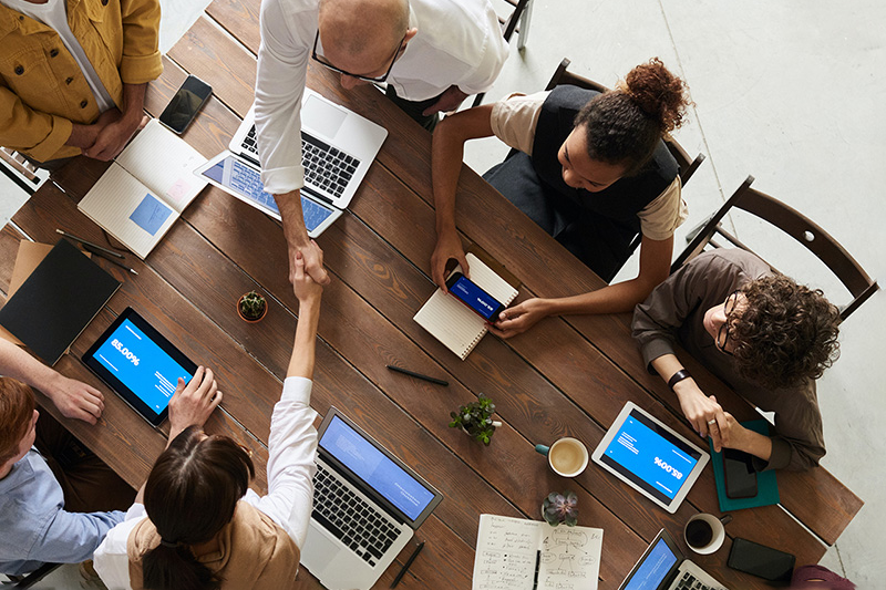 Group of people working around the table and two guys shaking hands